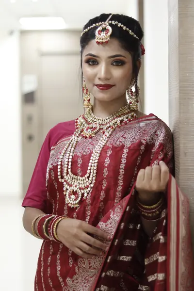 Bride in a red saree with heavy gold jewellery and a maang tikka